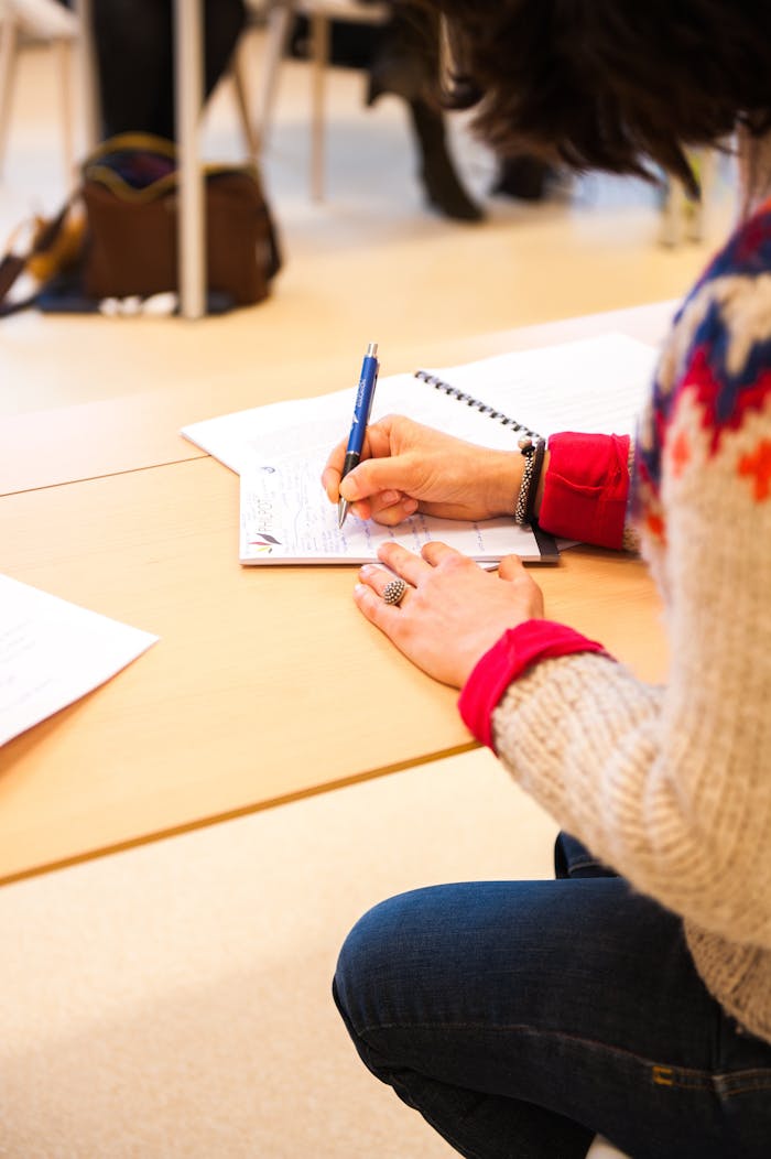 Más de 405 mil personas en Chile no saben leer ni escribir A woman writing notes in a notebook during a classroom lecture setting.